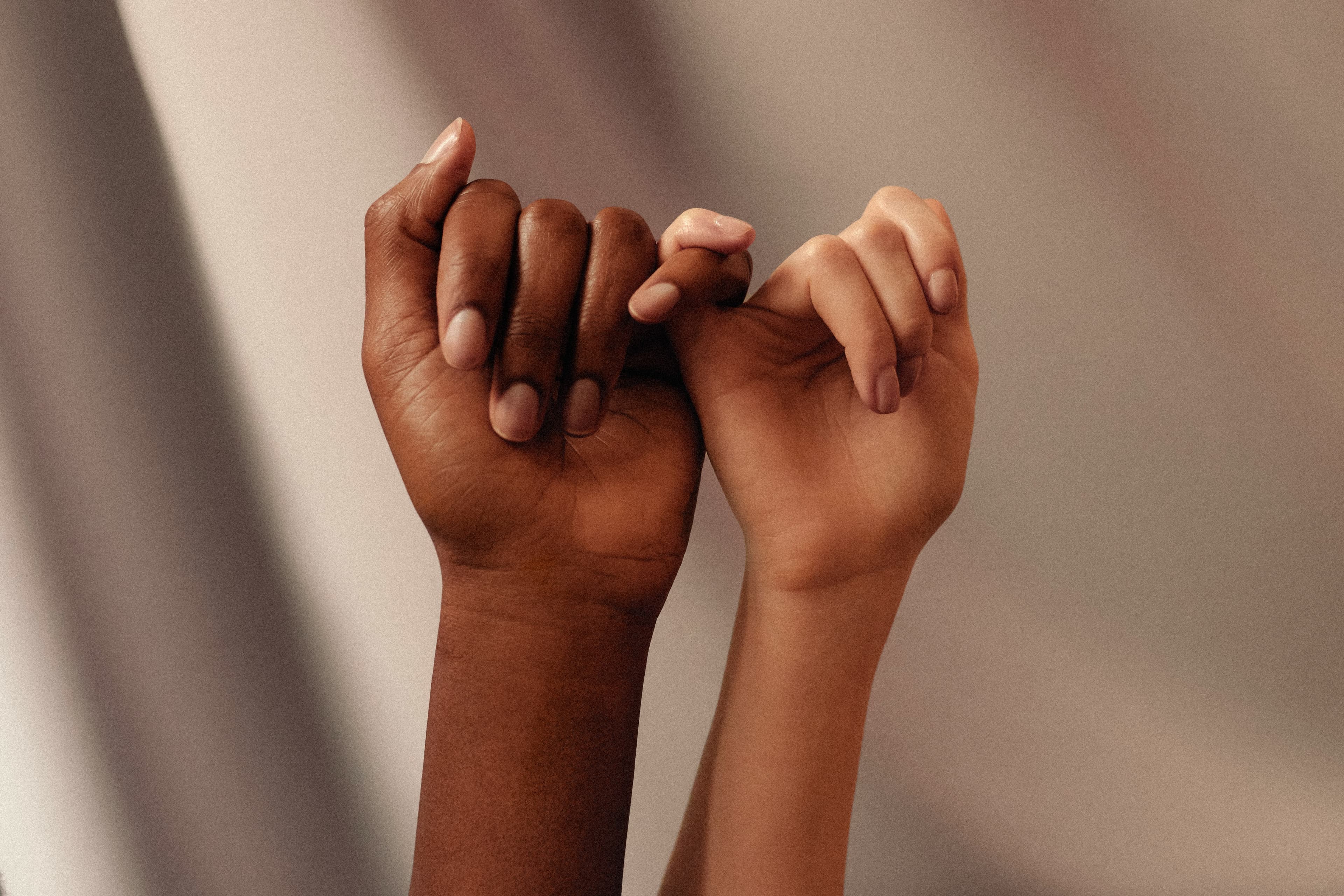 Warm-toned photograph of hands joined in a caring gesture